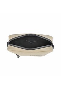 Borsa a pochette beige con una texture liscia, chiusura a zip e interno nero. Presenta un design minimalista e un dettaglio del logo impresso sul lato.