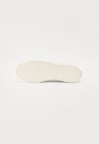 Cipőtalp, textúrált fehér gumi, enyhén megemelt mintázattal és sima szélekkel, minimalista dizájnnal, látható logók vagy jelzések nélkül.