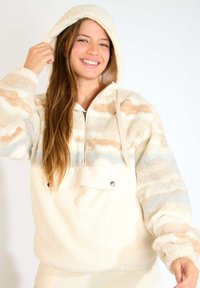 Felpa con cappuccio color crema in pile, caratterizzata da una zip frontale a metà, un pattern testurizzato con strisce pastello e una tasca frontale con dettaglio a pressione.