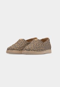 Paire de chaussures sans lacets en tissu imprimé léopard beige et noir avec semelles en caoutchouc beige clair sur fond uni clair.
