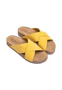 Sandalias de ante amarillo con un diseño abierto, con correas entrelazadas. Suela de corcho suave con una plantilla de color marrón texturizada.