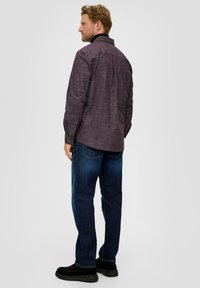 Rot-weißer gestreifter Hemd mit langen Ärmeln, Knopfmanschetten und Rückenpasse, kombiniert mit blauen Jeans und schwarzen Schuhen.
