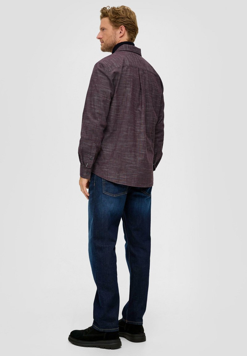 Camisa de rayas rojas y blancas con mangas largas, puños con botones y un yugo trasero, combinada con jeans azules y zapatos negros.