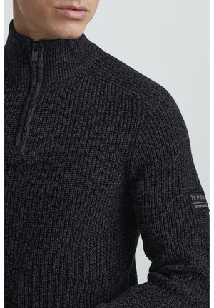 Sort strik sweatshirt med høj krave, halv lynlås foran og struktureret stof. Har et logo-patch på venstre ærme.