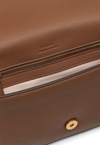 Borsa in pelle marrone con finitura testurizzata, zip dorata e chiusura a scatto. Interno con morbida fodera beige e una tasca slanciata.