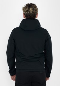 Giacca nera con cappuccio dal tessuto liscio, con spalle fitte e orlo leggermente elasticizzato. Nessun logo visibile o pattern distintivi.