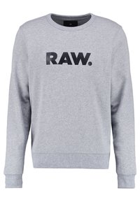 Sudadera gris de manga larga, con puños y dobladillo acanalados, que presenta un atrevido texto negro "RAW." en la parte frontal. Textura suave, diseño informal.