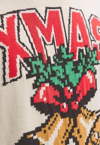 Maglione lavorato a maglia con la scritta "XMAS" in lettere rosse, design di foglie verdi e bacche rosse su uno sfondo crema, accentuato da contorni neri.