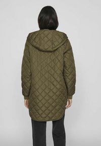 Olivgrön vadderad långjacka med huva, prydd med diamantmönster, ribbade muddar och en lätt rundad nederkant.