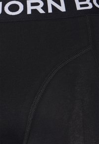 Schwarze Baumwoll-Boxershorts mit einem weißen elastischen Bund, auf dem "BJORN BORG" steht. Glatte Textur mit flachen Nähten und einer eng anliegenden Passform.