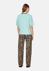 Light blue short-sleeve t-shirt with a black leopard print neckline paired with wide-leg, brown and black leopard print pants.