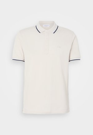 Cremfarbendes Polo-Shirt mit einer Knopfleiste mit drei Knöpfen, kurzen Ärmeln und Akzenten in Marineblau an Kragen und Ärmeln. Weicher Baumwollmischstoff.