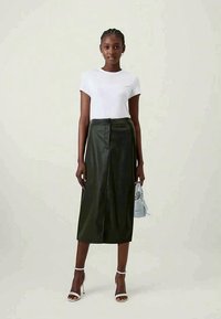 White short-sleeve T-shirt paired with a dark green leather midi skirt featuring a front button and zipper closure. Accented with a light blue handbag.