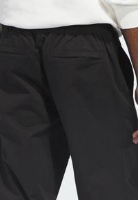 Μαύρο παντελόνι χαλαρής εφαρμογής με ελαστική μέση, διαθέτει δύο πίσω τσέπες και λείο ύφασμα.