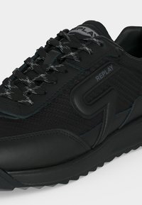 Baskets noires Replay avec panneaux latéraux texturés, détails de marque et lacets noirs avec accents blancs.