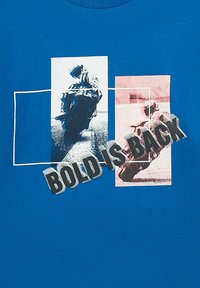 Blaues Baumwoll-T-Shirt mit grafischen Drucken von Motorradfahrern in Schwarz und Rot, mit dem Text "BOLD IS BACK" in Grau über dem Design.