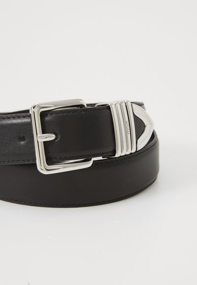 Schwarzer Leder Gürtel mit einer silbernen rechteckigen Schnalle, die vertikale Rillen und eine pfeilförmige Akzentuierung aufweist. Glatte Textur, minimalistisches Design.