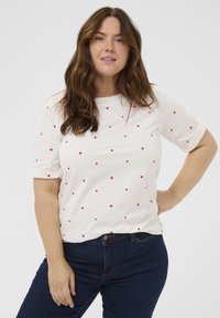 Weißes T-Shirt mit kurzen Ärmeln und verstreuten kleinen roten Herzmustern; kombiniert mit dunkelblauen Jeans; hat eine lockere Passform und einen Rundhalsausschnitt.