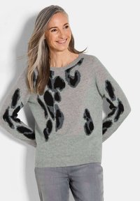 Hellgrauer Pullover mit schwarzen Leopardenmuster, rundem Halsausschnitt, langen Ärmeln und weicher Textur, kombiniert mit grauen Hosen.