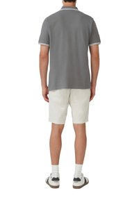 Grijze poloshirt met witte afwerking, gecombineerd met lichtgekleurde shorts. De stof lijkt zacht en casual, ontworpen voor comfort.