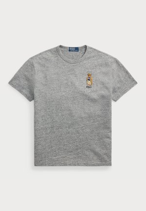 Graues kurzärmeliges T-Shirt mit Rundhalsausschnitt und kleinem gesticktem Bären, der einen blauen Pullover und eine beige Jacke über dem Schriftzug „POLO“ auf der Brust trägt.