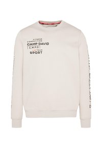 Lys beige sweatshirt med rund hals, lange ærmer og ribbede manchetter. Har trykt tekst i sort og orange, med branding på fronten og ærmerne.