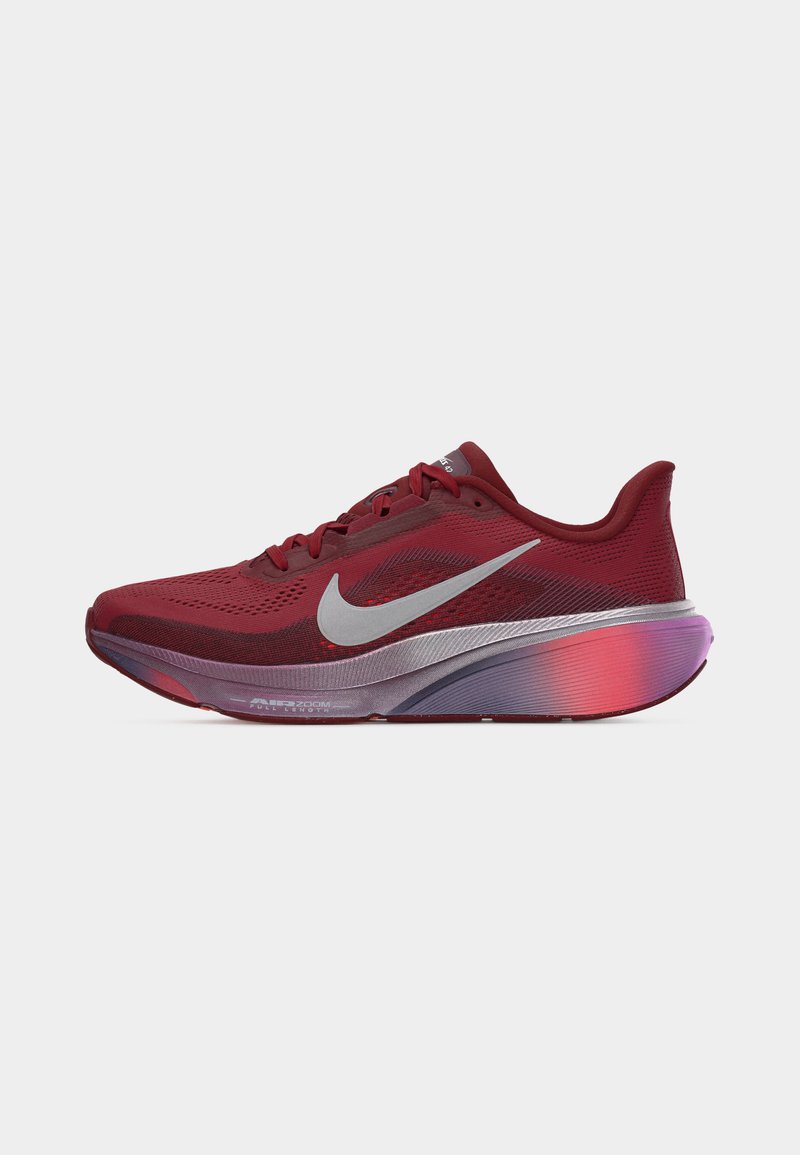 Chaussure de course Nike rouge avec un swoosh argenté proéminent, une tige en mesh respirant et une semelle épaisse en dégradé de tons violet et rouge.
