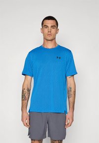 Sinine sportlik T-särk tekstuurse triibulise mustriga, ümar kaelus, lühikesed varrukad ja väike must logo vasakul rinnal.