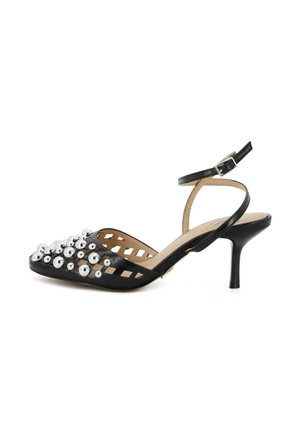 Décolleté slingback in pelle nera con punta appuntita, borchie sferiche argentate e lati traforati, dotata di cinturino alla caviglia con fibbia.