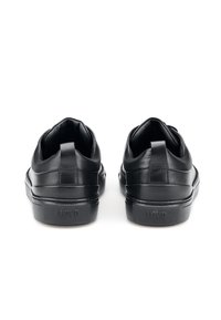 Sneakers in pelle nera con finitura liscia, design a basso profilo, collare imbottito e suola in gomma testurizzata con il nome del brand sul tallone.
