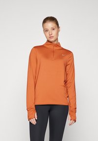 Pánska dlhá rukávová poloverzá s elastickým zipsom v oranžovej farbe s hladkou textúrou a otvormi na palce. Obsahuje malé biele logo Nike na hrudi.