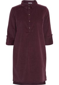 Burgundowy sukienka z kordurowego materiału z zapięciem na guziki, kołnierzykiem i rękawami o długości trzech ćwierć. Posiada podwinięte mankiety i prosty krój.