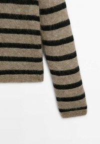 Sweter dzianinowy w beżowej bazie z czarnymi poziomymi paskami. Posiada miękką, puszystą teksturę i krótki krój z długimi rękawami.