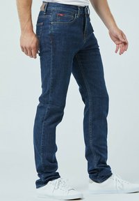 Donkere spijkerbroeken met een slim fit ontwerp, vijf zakken stijl en subtiele stikdetails. Draag met witte sneakers.