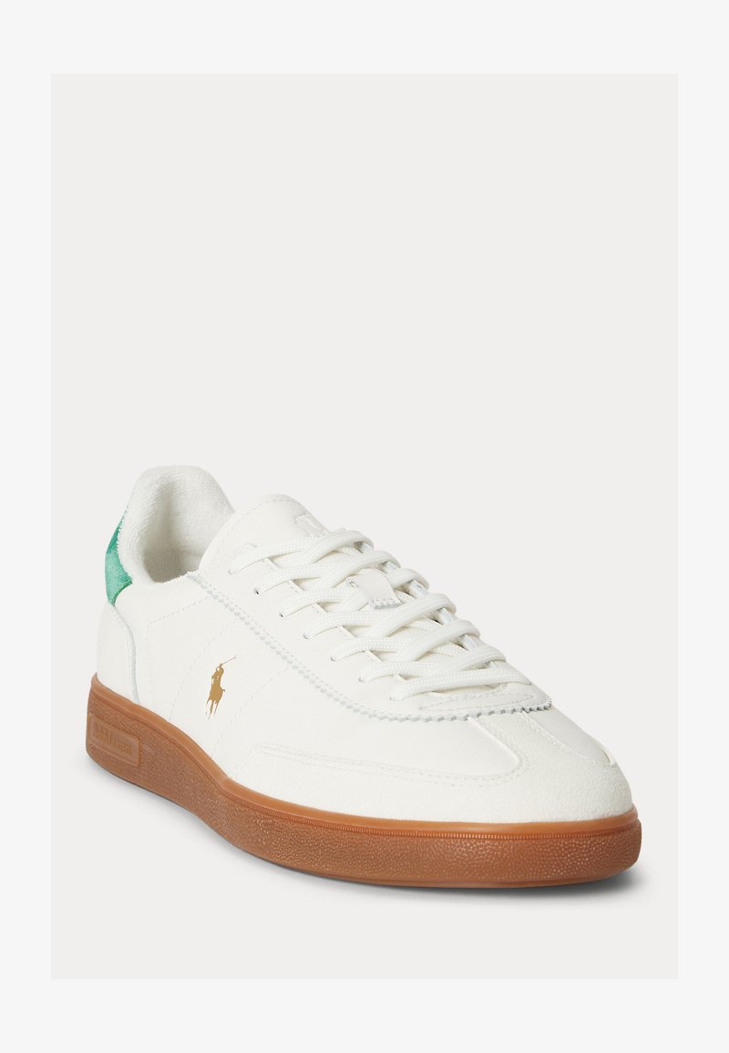 Λευκό sneaker με κορδόνια, καφέ καουτσούκ σόλα, πράσινο ταμπελάκι στη φτέρνα και μικρό χρυσό λογότυπο παίκτη πόλο στο εξωτερικό μέρος.