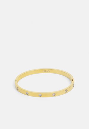 Guld armbåndsarmbånd med et glat, strømlinet design og fem klare rhinsten jævnt fordelt langs båndet. Indgraveret logo indeni.