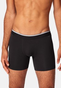 Schwarze Boxershorts aus glattem Stoff, mit schmaler Passform, elastischem Bund mit grauen Akzenten und konturiertem Beutel.