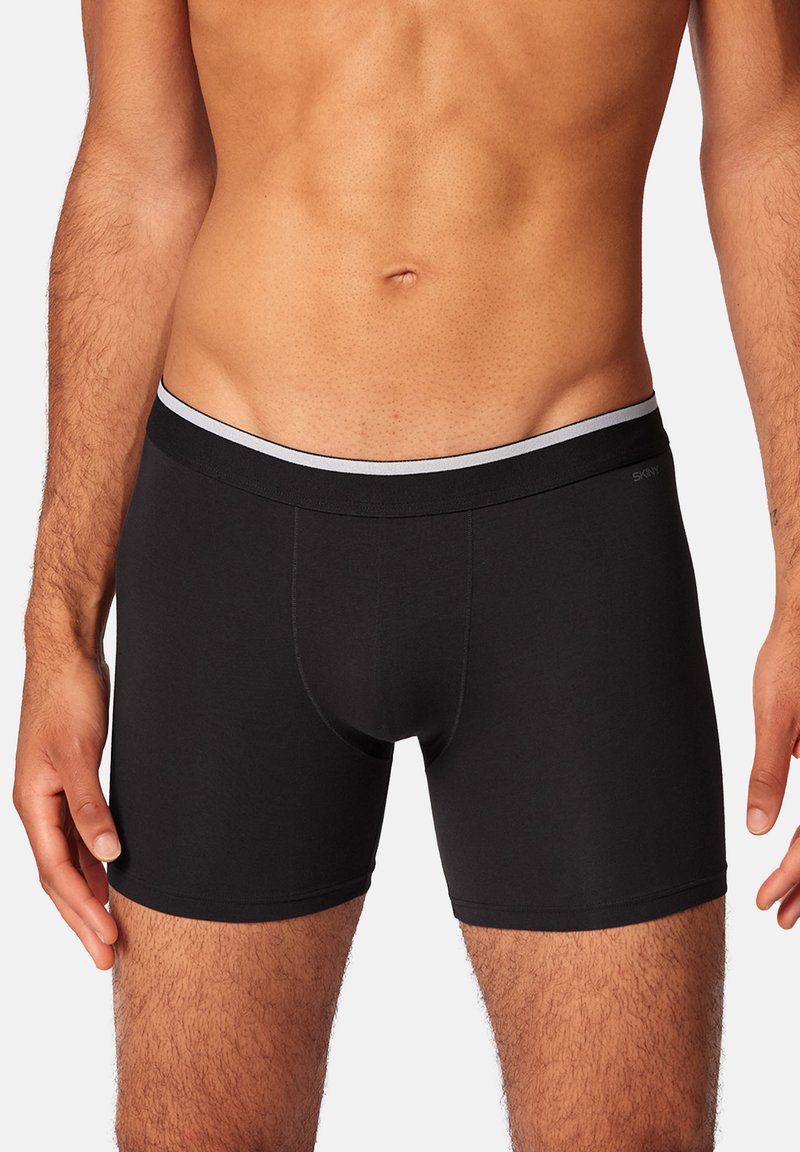 Schwarze Boxershorts aus glattem Stoff, mit schmaler Passform, elastischem Bund mit grauen Akzenten und konturiertem Beutel.
