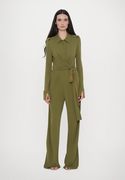 Salopette verde oliva con apertura a bottone, design avvolgente e pantaloni a gamba larga. Caratterizzata da un colletto e dettagli con fiocco in vita.
