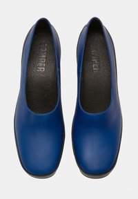 Chaussures en cuir bleu avec une texture lisse, bout arrondi et design minimaliste. Intérieur noir et marque discrète visible sur la semelle intérieure.