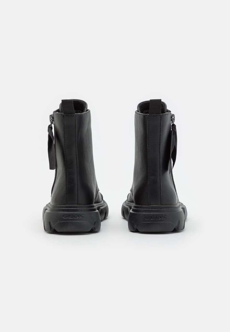 Schwarze Leder-Stiefeletten mit glatter Textur, runder Spitze und Gummisohle. Mit einem Reißverschluss und einem Stoff-Band am Rücken.