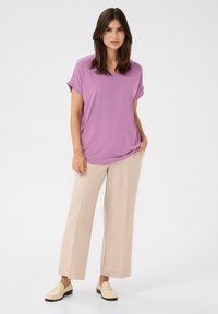 Lavanda brīvi krītoša blūze ar sarullētām piedurknēm, apvienota ar bēšiem platām biksēm un gaišiem mokasīniem. Gluda auduma tekstūra.