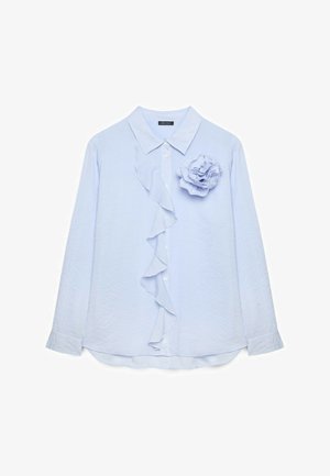Jasnoniebieska bluzka z długim rękawem w subtelne paski, z guzikami z przodu, falbanką wokół guzików oraz dużym materiałowym kwiatem na lewej piersi.