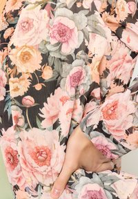 Ziedu kimono, kas izgatavots no caurspīdīgas auduma ar lieliem rozā peonijām un zaļumiem. Tam ir plūstoša forma un smalks zelta akcentējums.