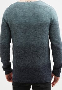 Maglione lavorato a maglia blu scuro con una sfumatura dal chiaro allo scuro, maniche lunghe, collo rotondo, motivo testurizzato e polsini a coste sulle maniche.