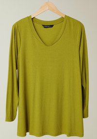 Olivgrünes Langarmshirt mit tiefem V-Ausschnitt, gerippter Textur und lockerer Passform, präsentiert an einem Holzkleiderbügel vor einem neutralen Hintergrund.