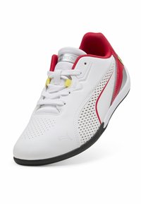 Zapatilla deportiva blanca con acentos rojos, diseño perforado, lengüeta de malla blanca texturizada y suela de goma negra. Presenta cordones amarillos y logotipo.