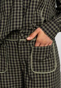 Chemise et pantalon à motif vichy en vert foncé et noir, dotés d'une coupe décontractée, d'une taille ajustable et de grandes poches avant.