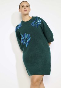 Groene gebreide jurk met oversize korte mouwen, versierd met blauwe pailletten bloemenapplicaties aan de voorkant, zachte textuur en ontspannen pasvorm.