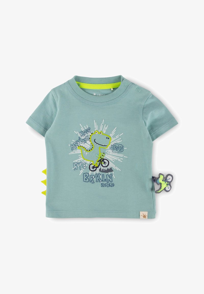 Light blue short-sleeve cotton T-shirt featuring a dinosaur graphic, vibrant green accents, and yellow side spikes. Text includes "KEEP MOVING."